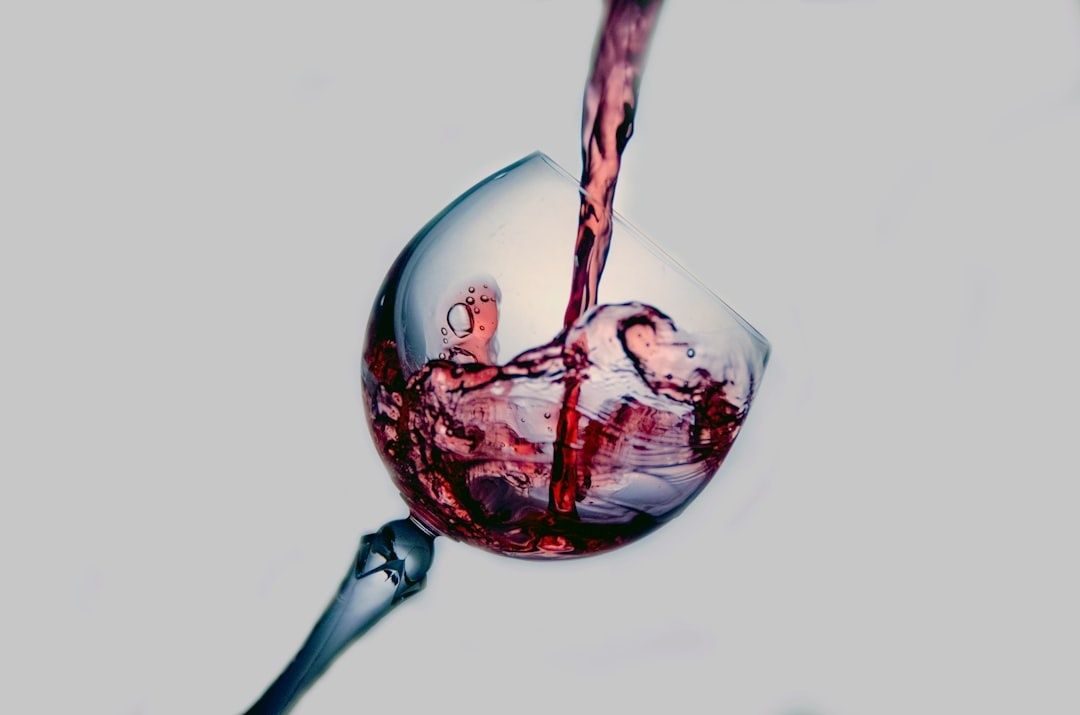Vin rouge versé dans un verre à pied transparent